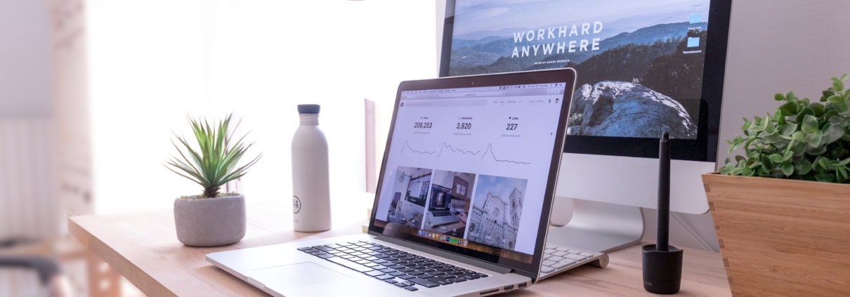 A laptop sitting on a desk with a large monitor, plant, and water bottle. Featured in Digital Agent's Internet Guide for Small Businesses